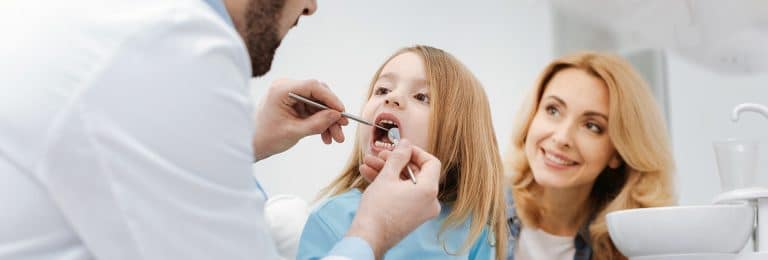 O femeie isi spala pe dinti fiicei sale intr-un cabinet stomatologic din Bucuresti.