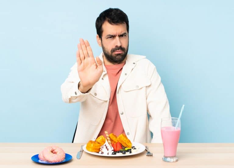 Un bărbat care stă la o masă cu o farfurie cu mâncare și un semn de stop în Rahova, Sector 5.