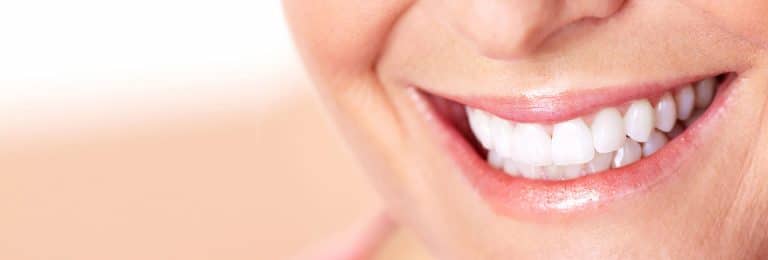 Un prim plan al zâmbetului unei femei la dentist.