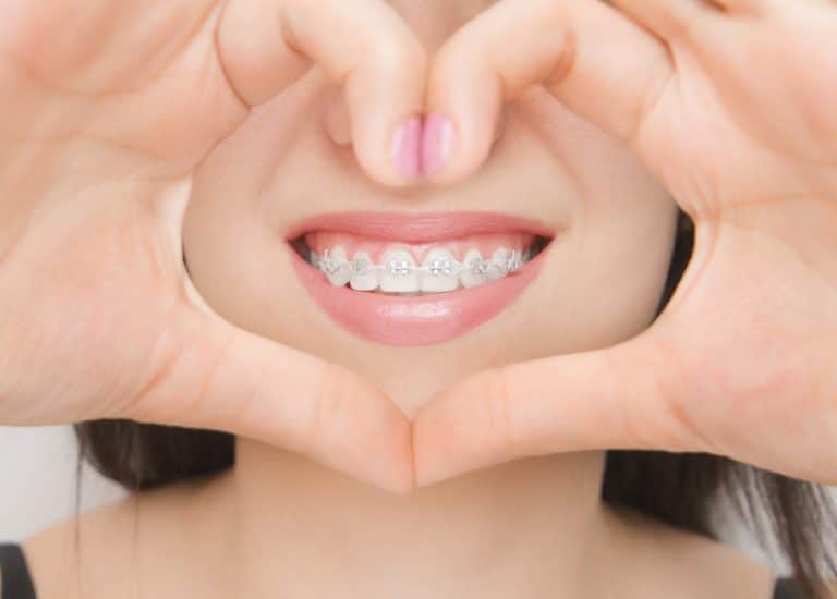 O femeie cu aparat dentar în sectorul 5 care face o inimă.