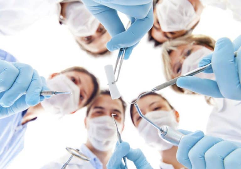 Un grup de medici din Rahova ținând în cerc instrumentele dentare.